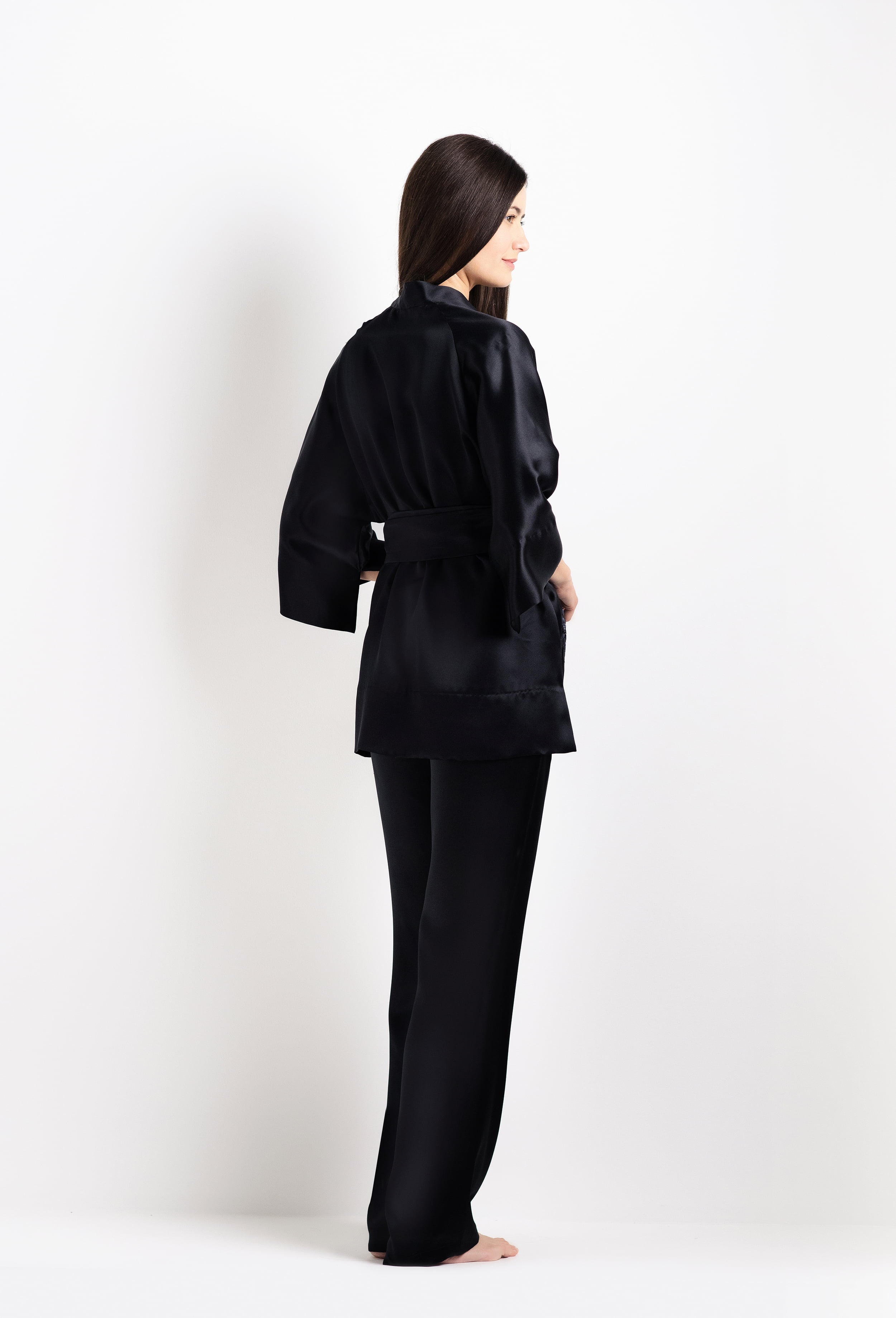 Person wearing a black satin robe on a white background