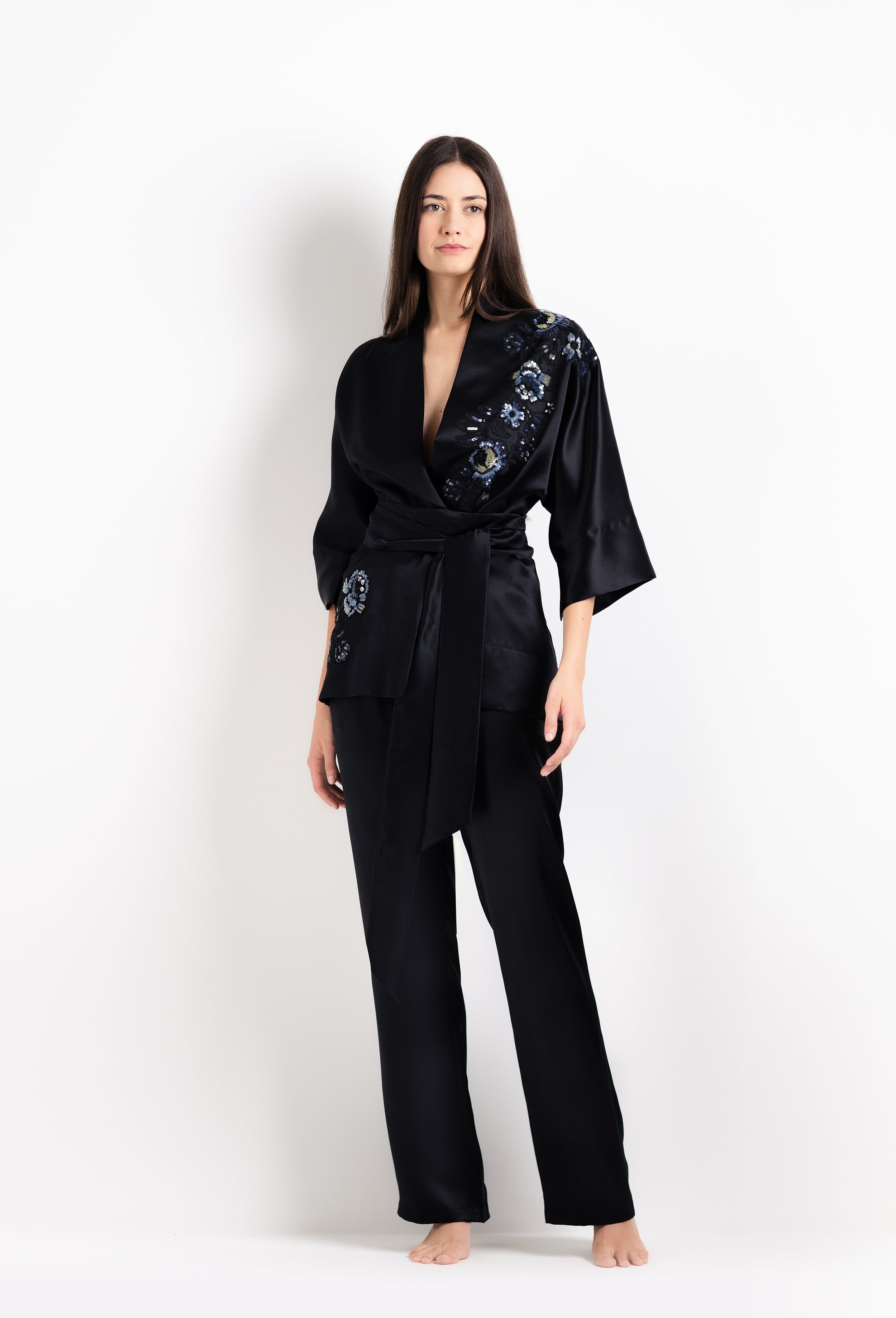 Woman wearing a black satin robe with floral embroidery on a white background