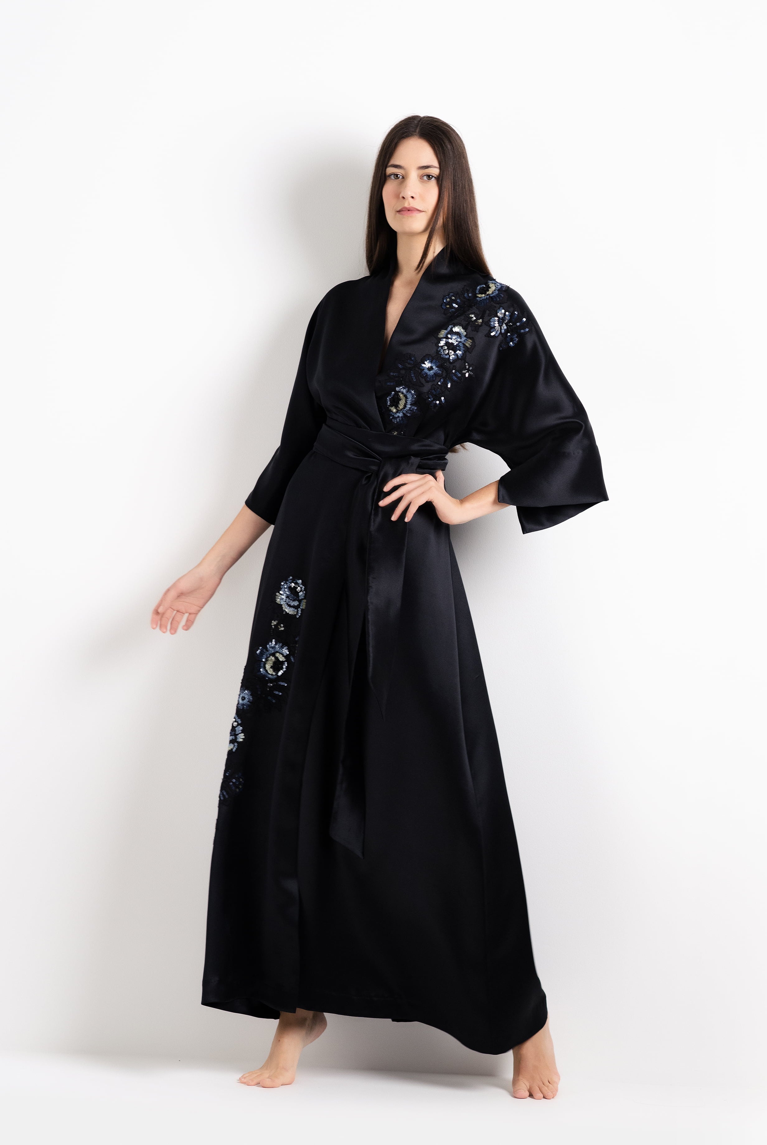 Woman wearing a black dress with floral embroidery on a white background