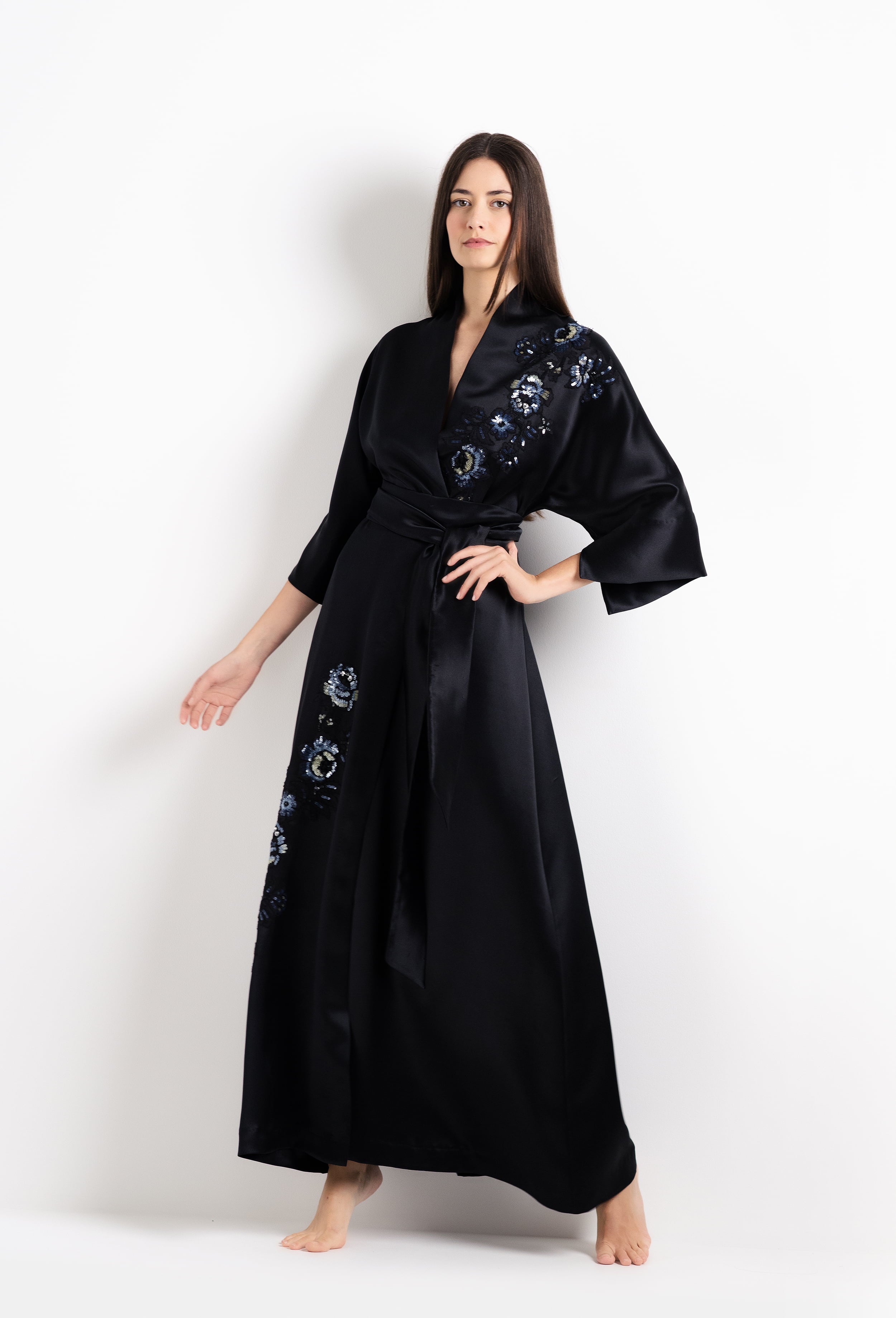 Woman wearing a black dress with floral embroidery on a white background