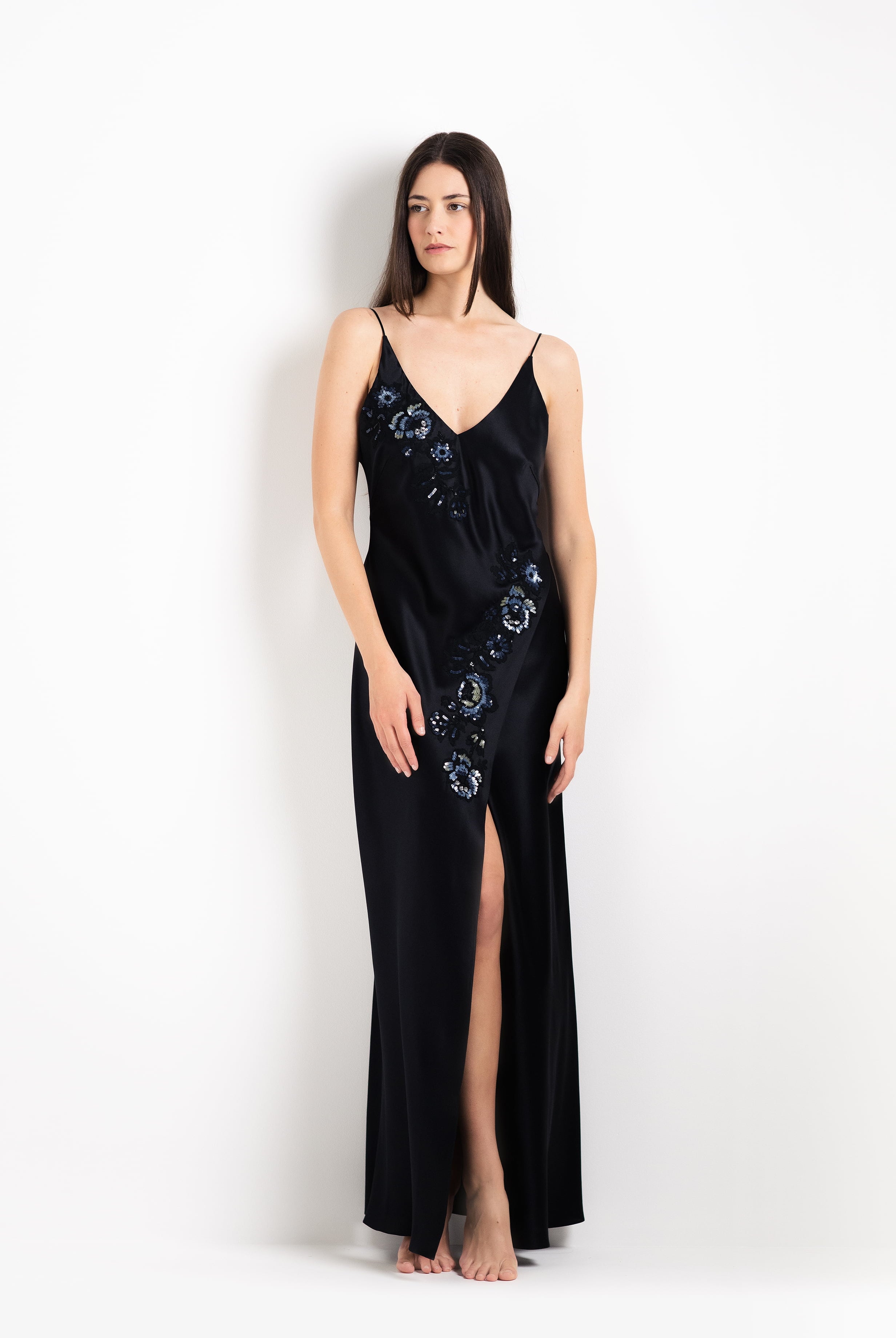 Woman wearing a black evening gown with floral embellishments on a white background