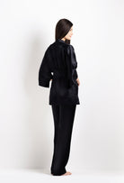 Person wearing a black satin robe on a white background